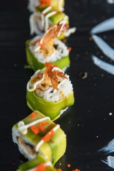 Various kinds of sushi served on wood black table.