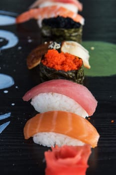 Various kinds of sushi served on wood black table.