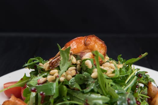 Green salad with shrimps: greens, arugula, tomato, pine nuts and sauce