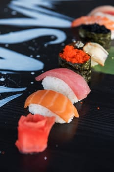 Various kinds of sushi served on wood black table.