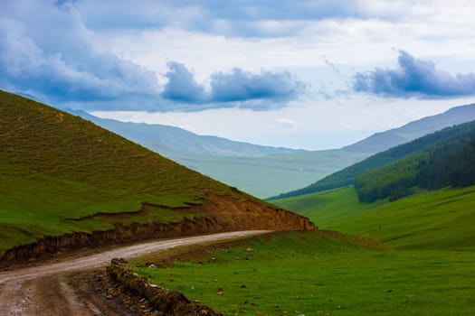 dirt road in the mountain hills at rainy summer day in Kyrgyzstan