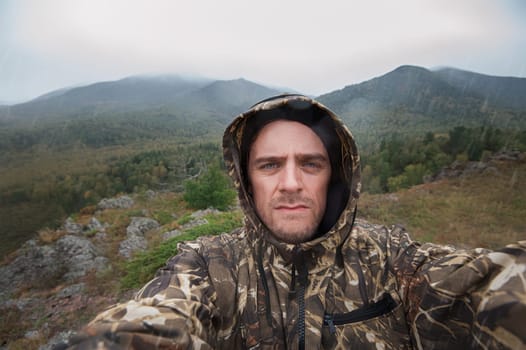 Caucasian man in the mountain making selfie on background nature landscape