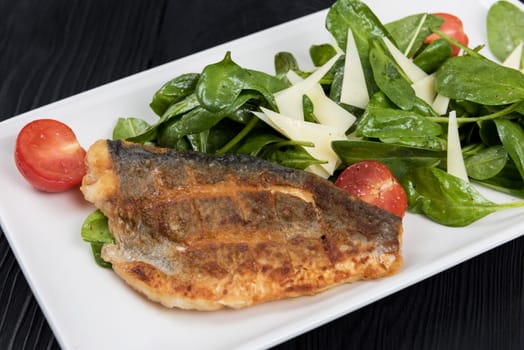 Grilled Dorado fish fillet with spinach, tomato and cheese