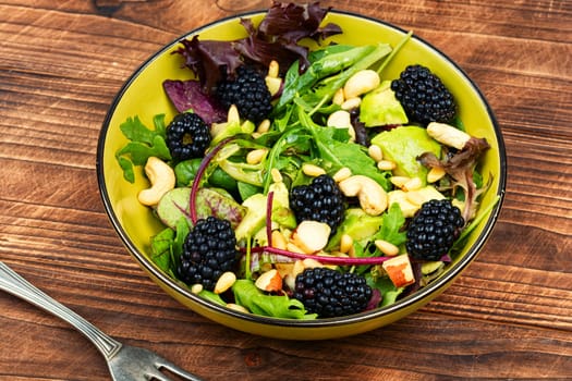 Vegan salad with blackberries, microgreens, avocado and pine nuts on a concrete kitchen table. Space for text.