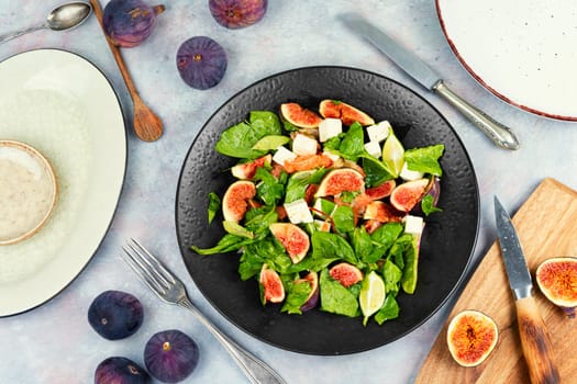 Vitamin salad with figs, greens and cheese on rustic wooden table..