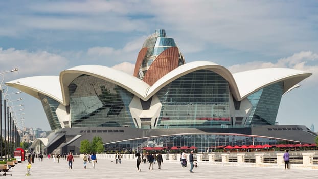 Baku, Azerbaijan - May 4, 2024: Visitors stroll along the walkway near Deniz Mall, enjoying the unique architecture and vibrant atmosphere during a sunny day
