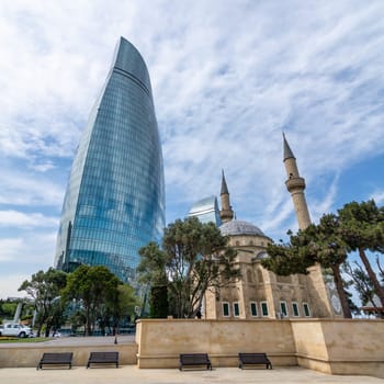 The Sehitler Mosque, or Mosque of the Martyrs stands prominently in front of the Flame Towers in Baku, Azerbaijan