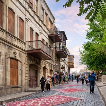 Baku, Azerbaijan - May 5 2024: First National Carpet Festival of Azerbaijan takes place in Old Town. Visitors stroll along cobblestone streets surrounded by beautiful carpets and historic architecture