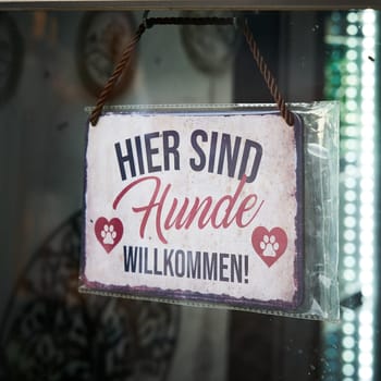 Sign with the German inscription hier sind Hunde willkommen, at a store for dog fashion in Germany. Translation: Dogs are welcome here