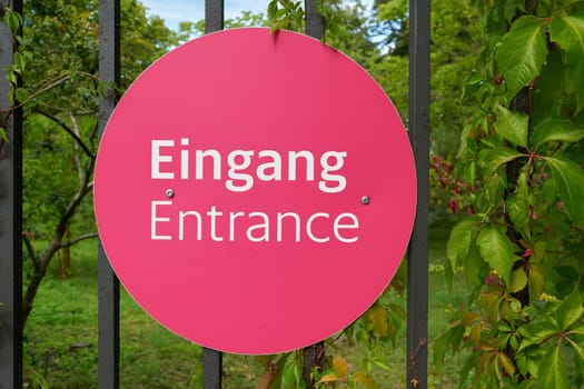 Sign on the fence to a park in Germany with the word Entrance in German and English