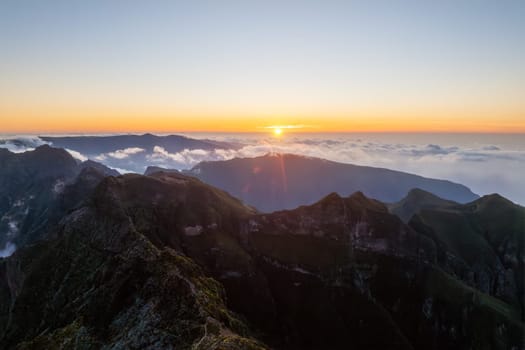 Aerial drone view of mountains over clouds near Pico Ruivo on sunset. Madeira island, Portugal