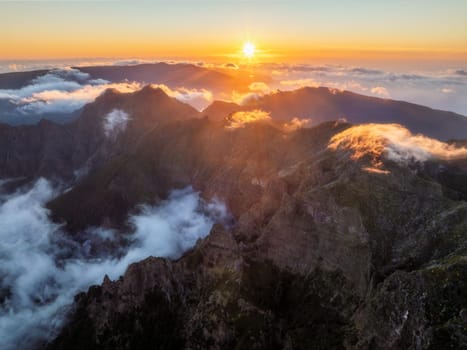 Aerial drone view of mountains over clouds near Pico Ruivo on sunset. Madeira island, Portugal