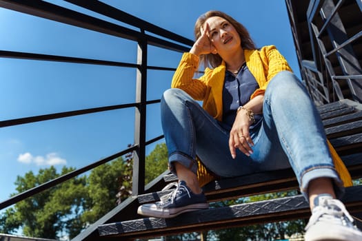 thoughtful woman sitting alone on outdoor stairs.