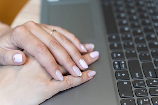 woman hands typing on laptop keyboard in a cafe.