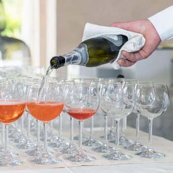 Barman serving orange liqueur cocktail in many wineglass. Bartender making spritz cocktail.