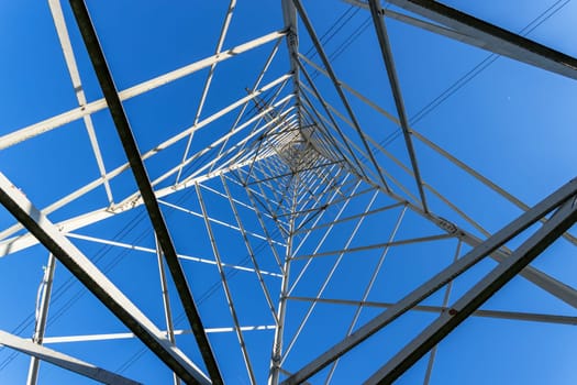 High Voltage Electricity Grid Pylon seen from below and blue sky