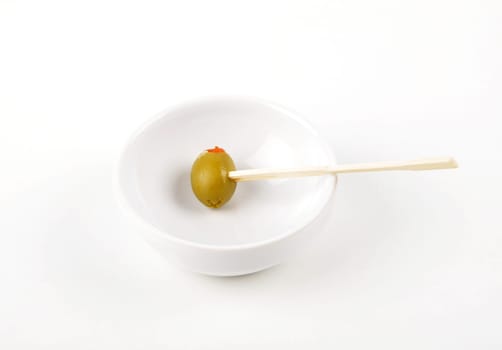 Olive with paprika on wooden skewer in porcelain bowl on white background
