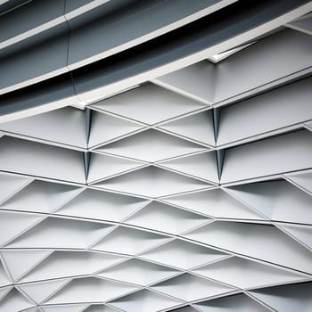 A unique ceiling showcases intricate geometric patterns, with a blend of triangles and diamonds. The neutral shades create an elegant ambiance, highlighting contemporary architectural style.