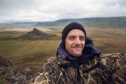 Caucasian man in the mountain making selfie on background nature landscape
