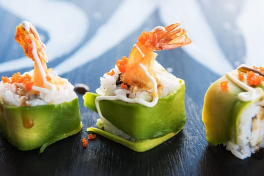 Various kinds of sushi served on wood black table.