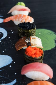 Various kinds of sushi served on wood black table.