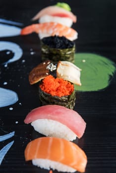 Various kinds of sushi served on wood black table.