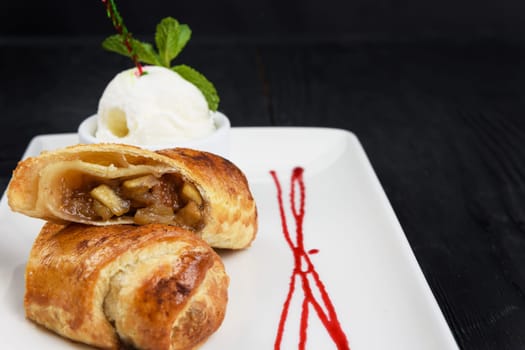Apple strudel with vanilla ice cream decorated with caramel and berries sauce