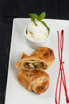 Apple strudel with vanilla ice cream decorated with caramel and berries sauce