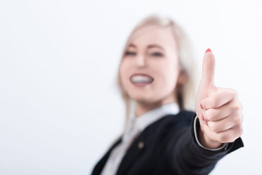 Happy businesswoman in a stylish suit gives a thumbs up sign, radiating positivity and approval in a professional setting