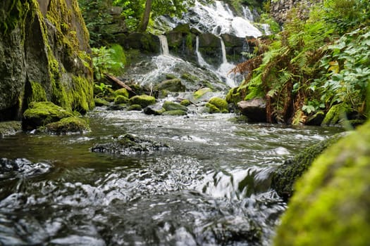 Small river in Sweden with several small waterfalls. Moss-covered stones. Forest on the shore. Scandinavian nature