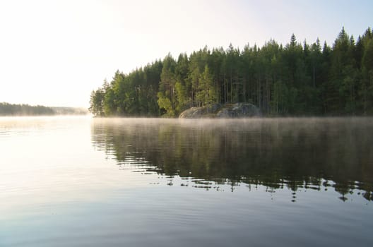 Lake in Sweden at sunrise with romantic light, blue water and trees on the shore. Scandinavian nature in the north