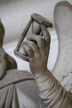 Antique statue holding a sandglass. Concept of time passing, countdown, retro hourglass
