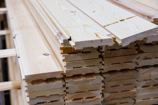 stacks of raw wooden tongue and groove boards, close-up view of the ends.