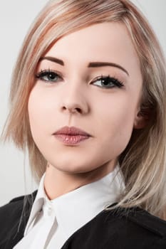 Confident young businesswoman with blonde hair poses in studio, exuding professionalism in black jacket and white shirt