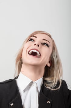 Cheerful young businesswoman is looking up and laughing heartily, her head tilted back against a plain white background