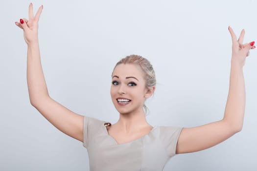 Joyful businesswoman celebrates success in her office, flashing a victory sign with a beaming smile