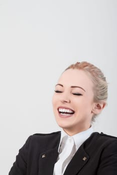 Young businesswoman with elegant blonde hair laughs with eyes closed against a white background, exuding confidence and joy