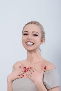 Attractive young woman with red nail polish is holding her hands to her chest and smiling broadly, expressing excitement and joy