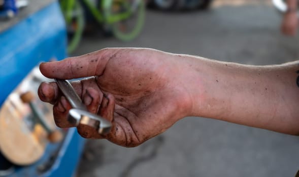 A man's hand is holding a wrench with dirt on it. Concept of hard work and manual labor