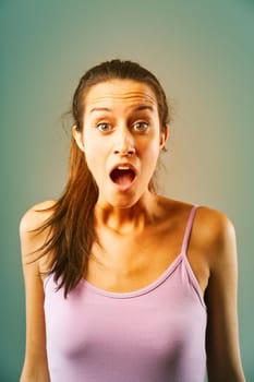 Young woman is gasping with her mouth wide open, raising her eyebrows and wrinkling her forehead, expressing shock and surprise