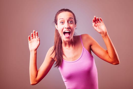 Young woman is shouting with her mouth wide open and her hands in the air, she could be experiencing fear, excitement, or surprise