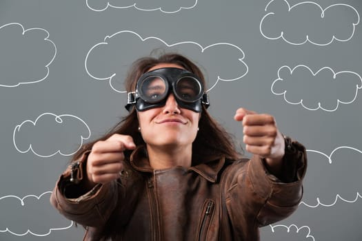 Confident young woman pretends to fly a plane through fluffy clouds, embodying freedom and adventure with a joyful smile and determined gaze