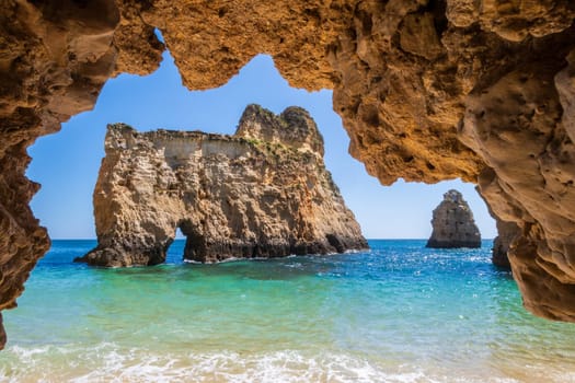 Small, heavenly and difficult to access beach photographed from inside a cave, near Portimão in the Algarve region of Portugal