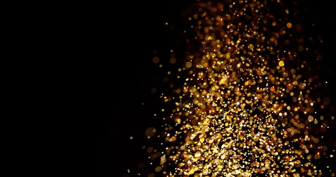 Gold glitter stardust trail on black background. Christmas golden spark border with space. Luxury new year holidayparty bokeh splash design.