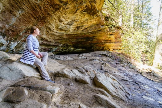 Female hiker taking rest in a small grotto in Red River Gorge in Kentucky