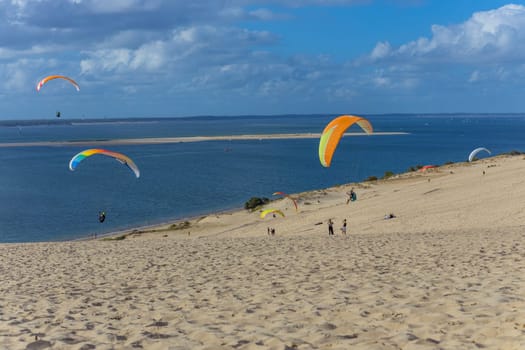 Dune of Pilat, France - August 14, 2024: People paragliding at the Great Dune of Pilat, Arcachon Basin, Nouvelle Aquitaine, France.