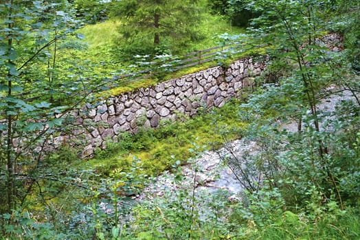 Stone wall in the Tyrolean Alps, a river in the foreground