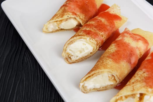 Pancakes or russian blini stuffed with cream sauce on a white plate.