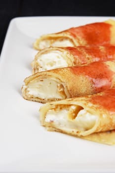 Pancakes or russian blini stuffed with cream sauce on a white plate.
