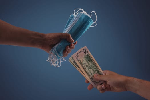 Sell - buy medical face mask concept. Hands holding protective face masks and nany US dollars banknote a lot of at.